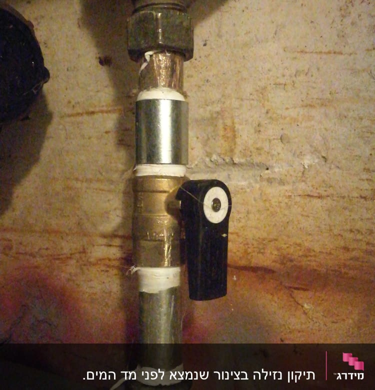צינור מתכת עם ברז שחור על רקע קיר